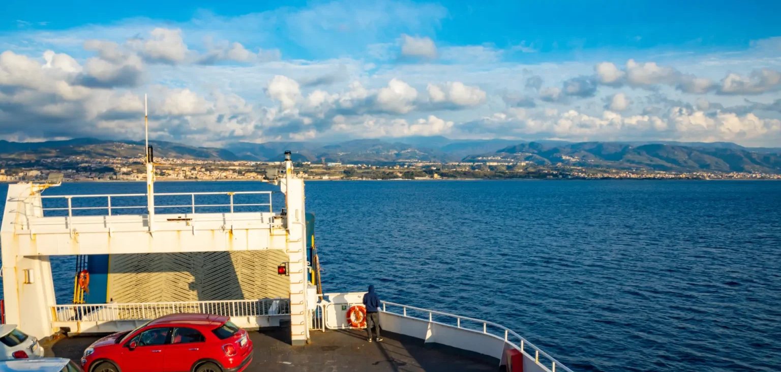 Cars parked on the open vehicle deck of a Croatian car ferry crossing the Adriatic, with the mainland coast in the distance